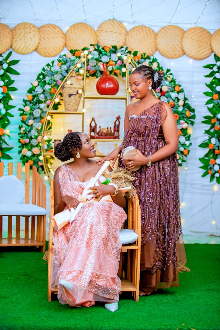 Two women in formal dresses at a flower-decorated celebration