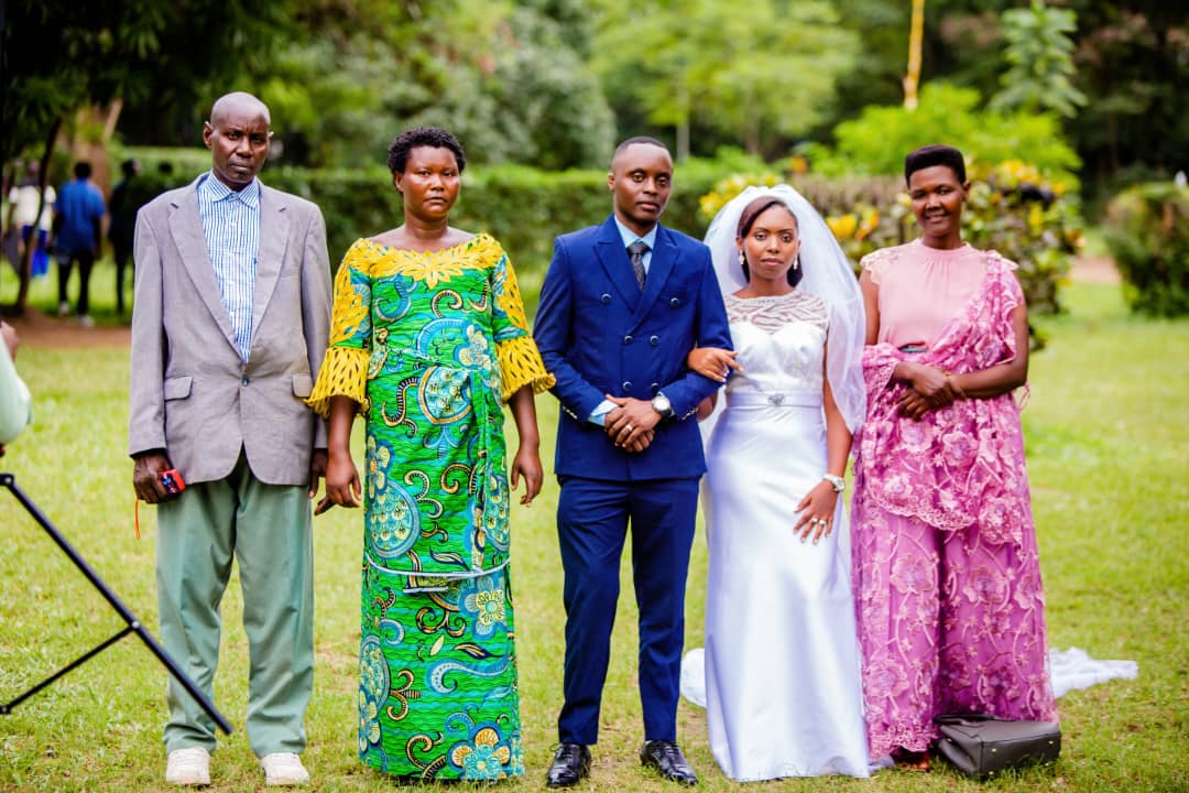 Bride and groom standing with three adults for a group wedding photograph in a garden